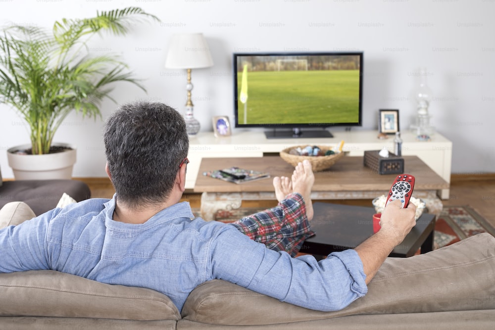 Hombre sentado cómodamente en el sillón mirando tele